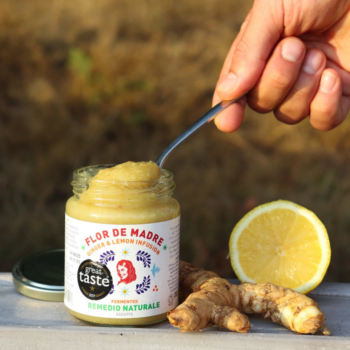 Hand holding a spoon dipped into Agua de Madre - Ferment Remedio Lemon & Ginger Infusion 250g