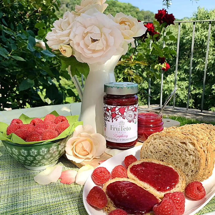 Frutteto Italia - Organic Raspberry Jam Lifestyle image with the jam on a table with fresh raspberries and bread