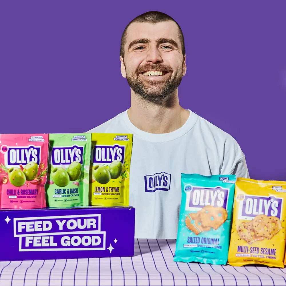 Olly's man with a selection of Olly's snacks olives and pretzels